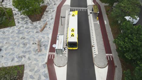 birds eye view of public transportation bus arriving at bus stop in clean city center of a ecological neighborhood