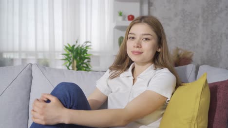 Mujer-Joven-Sentada-En-Un-Sofá-Mirando-A-La-Cámara-Y-Sonriendo.