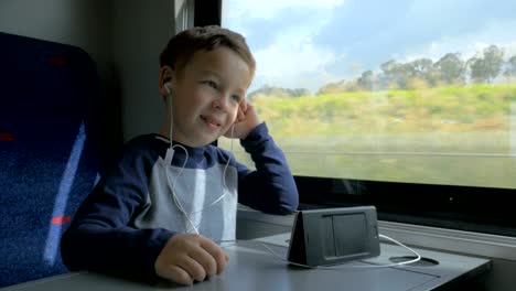 boy video chatting in train using cell and hands free set