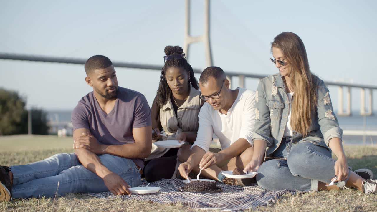 Happy young people waiting for delicious cake during picnic.