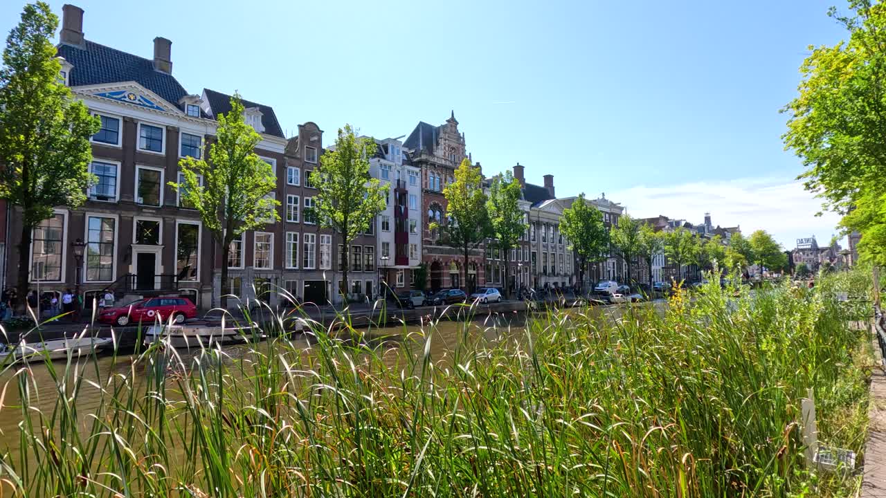 Daytime canal scene with Dutch houses, greenery, reflections, and gentle camera pan right