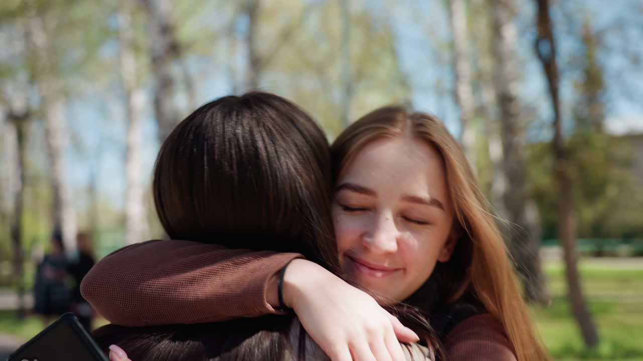 abrazo de amistad bajo el sol, dos amigos de diferentes orígenes abrazándose al aire libre en primavera, estudiantes alegres de diversos orígenes intercambian un cálido abrazo a lo largo de un camino frondoso durante la primavera