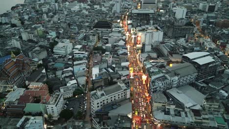 Antena-De-Yaowarat-Road,-La-Calle-Principal-Del-Barrio-Chino-De-Bangkok-Iluminada-Por-La-Noche-Con-Un-Letrero-De-Neón-Que-Vuela-Por-Encima