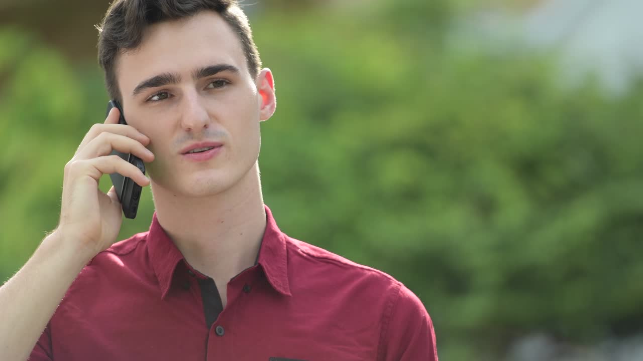 젊은 잘생긴 사업가가들이 거리에서 전화로 이야기하고 있습니다.