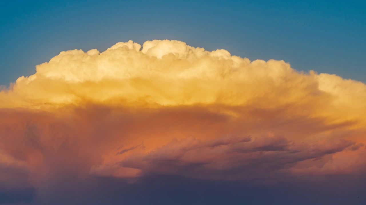 Golden light shining across moving clouds in a colorful sunset sky