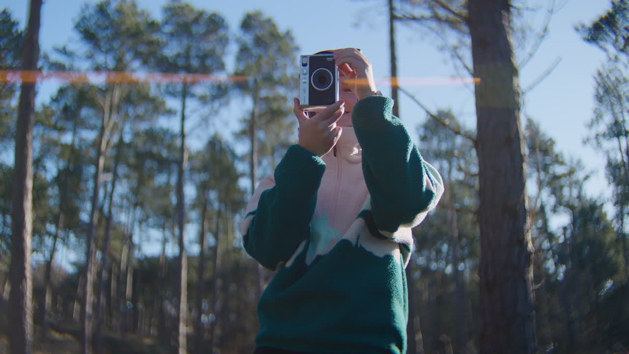 Handheld low angle shot of woman taking photos in woods on sunny day - Slowmotion