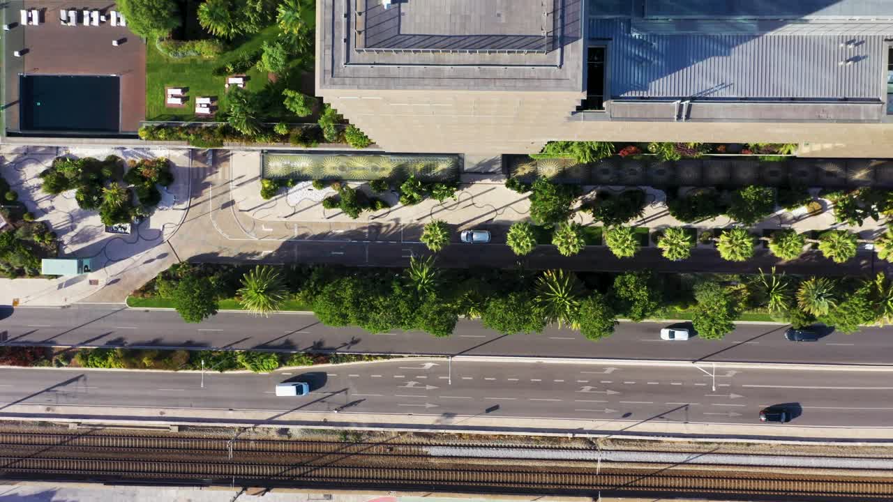 Overhead View Of Cars Driving Along The Railway Tracks And Apartment Buildings In Cascais, Portugal. - aerial shot