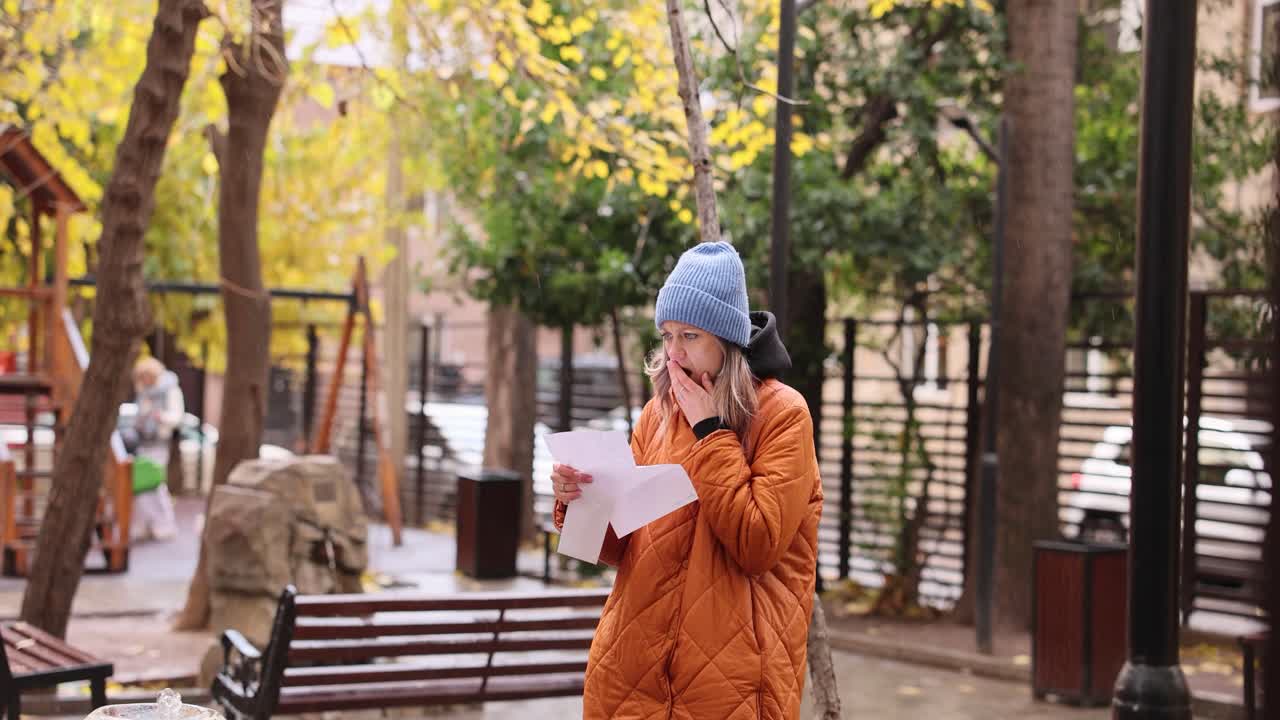 Woman reading surprising news in park