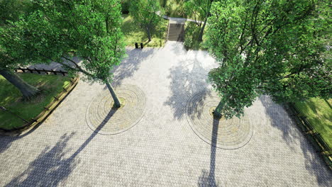 view of a sunny park with trees and patterned stone pavement in the afternoon