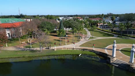 People-walk-past-Christmas-tree-and-decorations-beside-lake-mirror-in-downtown-Lakeland-Florida-during-the-holiday-season