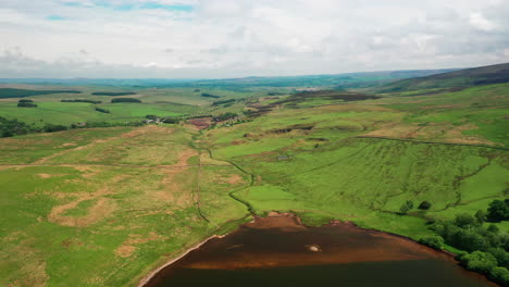 aerial landscape of the green countryside, with a lake and stream in shot, bright sunny day