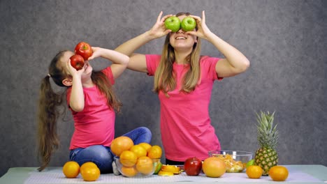mother and daughter with fruit. happy little girl with mother having fun and looking through apples