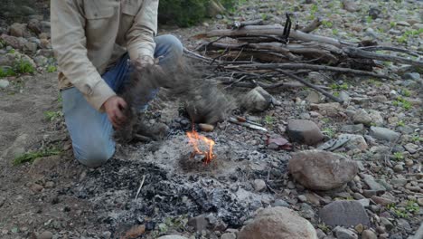 a close up shot of a bushman lighting a campfire by a river