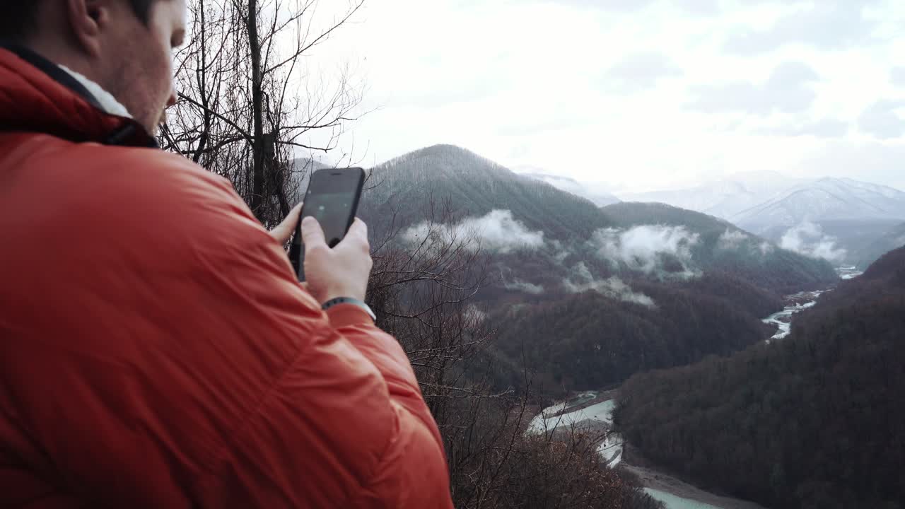 hombre tomando fotos de un paisaje de montaña