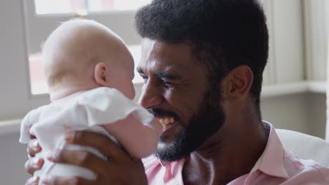 Loving-Father-Playing-With-Smiling-Baby-Daughter-Lifting-Her-In-The-Air-At-Home