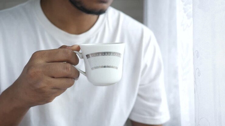 Mand holder kaffekop ved vinduet