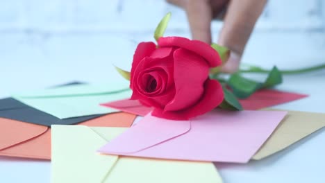 sobres de colores y una rosa roja