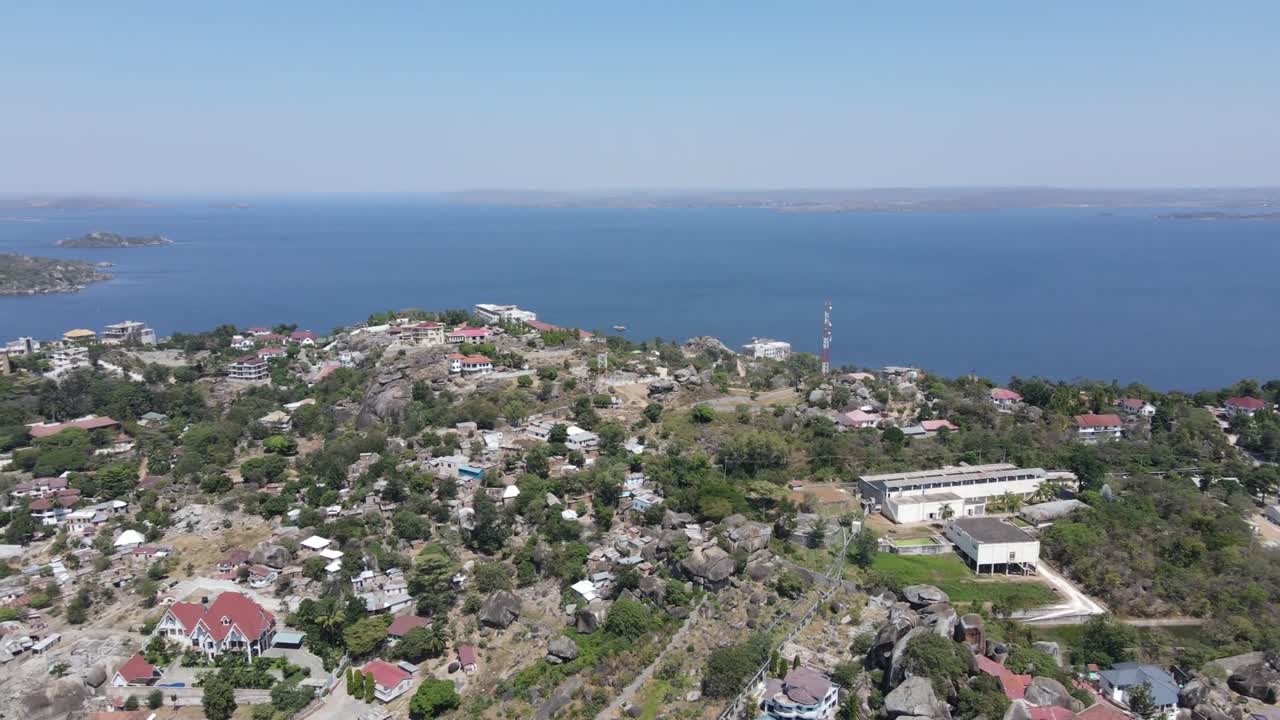 An HD drone pan shot over lush green hills overlooking Lake Victoria in Africa. Captures the serene waters, vibrant landscape, and stunning horizon.