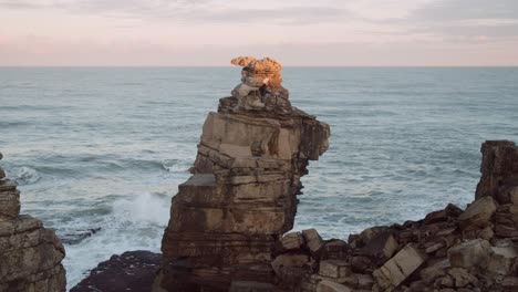 single cliff or rock on rocky coast of cascais in portugal, ocean waves in background, stable copyspace view