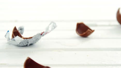 broken chocolate easter eggs falling on wooden surface