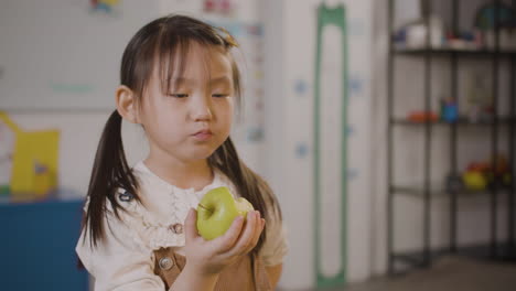 Kleines-Mädchen,-Das-Einen-Apfel-Im-Klassenzimmer-In-Einer-Montessori-Schule-Isst