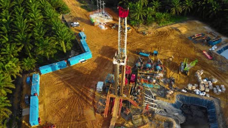 imágenes cinematográficas de drones de 4k de la estructura del equipo de la plataforma de perforación en tierra para la exploración y explotación de petróleo en medio de la jungla rodeada de palmeras durante la puesta de sol y el alto precio del petróleo