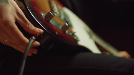 guitarist connecting jack plug to electric guitar in recording studio