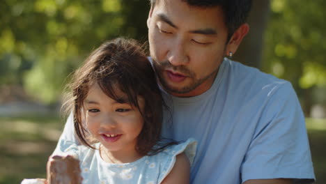 Close-up-of-happy-father-and-daughter-sitting-with-chocolate-ice-creams