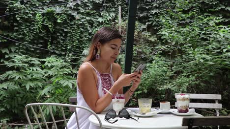 Girl-At-Cafe-Checking-Phone-Smiling