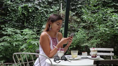girl at cafe checking phone smiling