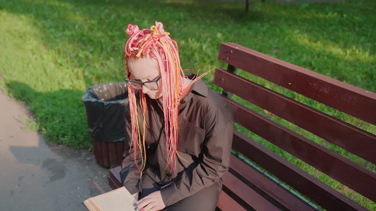 Mujer contemplativa sentada plácidamente en un banco; dama apacible que contempla en silencio mientras descansa en el parque; mujer tranquila con tristeza contenida que mira suavemente sus manos durante una reflexión silenciosa.