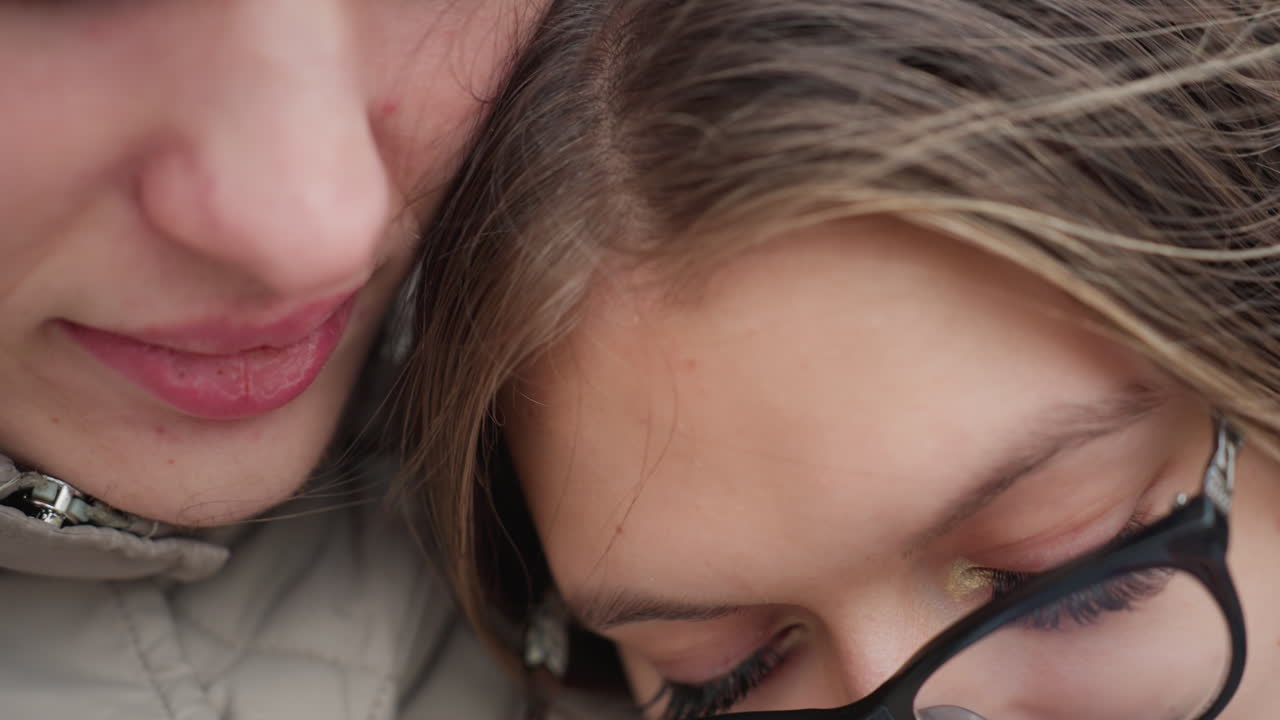 Close up romantic moment of man gently kissing woman head as she leans close in peaceful embrace, capturing tender connection and warmth between lovers with natural background