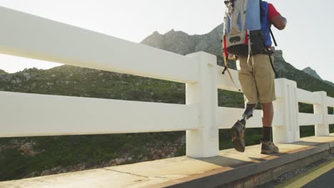 mixed race man with prosthetic leg hiking on road side