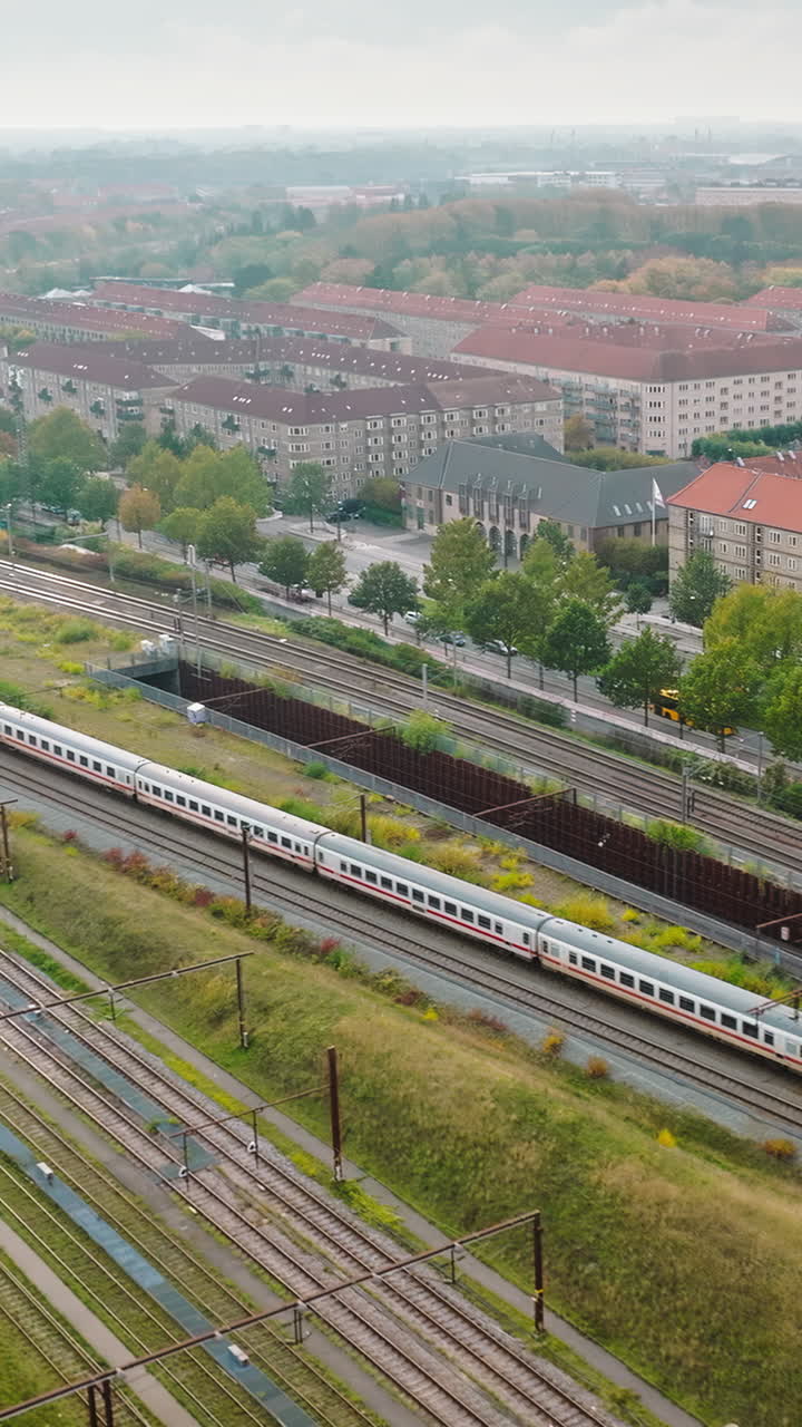 Aerial drone view of a train moving on the tracks near Vesterbro district in Copenhagen, Denmark. Vertical