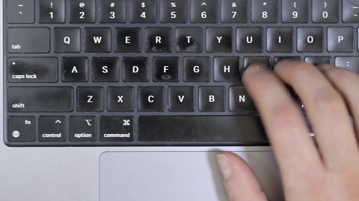 Overhead view of a blurry coffee cup next to a modern laptop keyboard