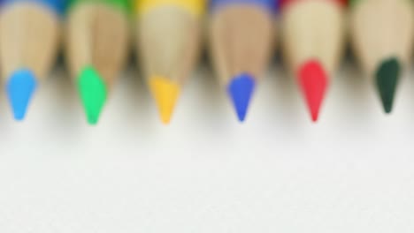 different colored pencils organized in a row on white background - rack focus