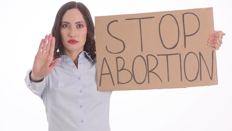 woman holding a "stop abortion" sign and making a stop gesture