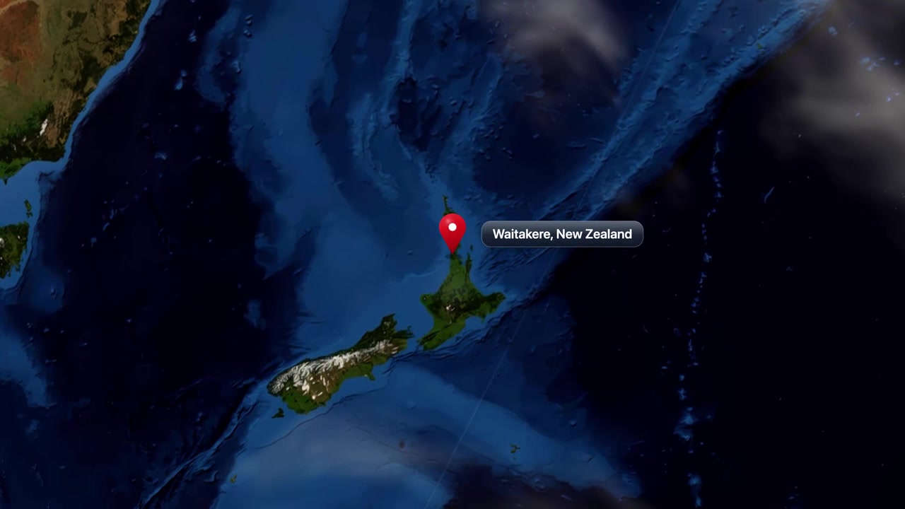 Satellite view zooming from outer space into New Zealand, revealing a pin on Waitakere. Includes NASA public domain imagery.
