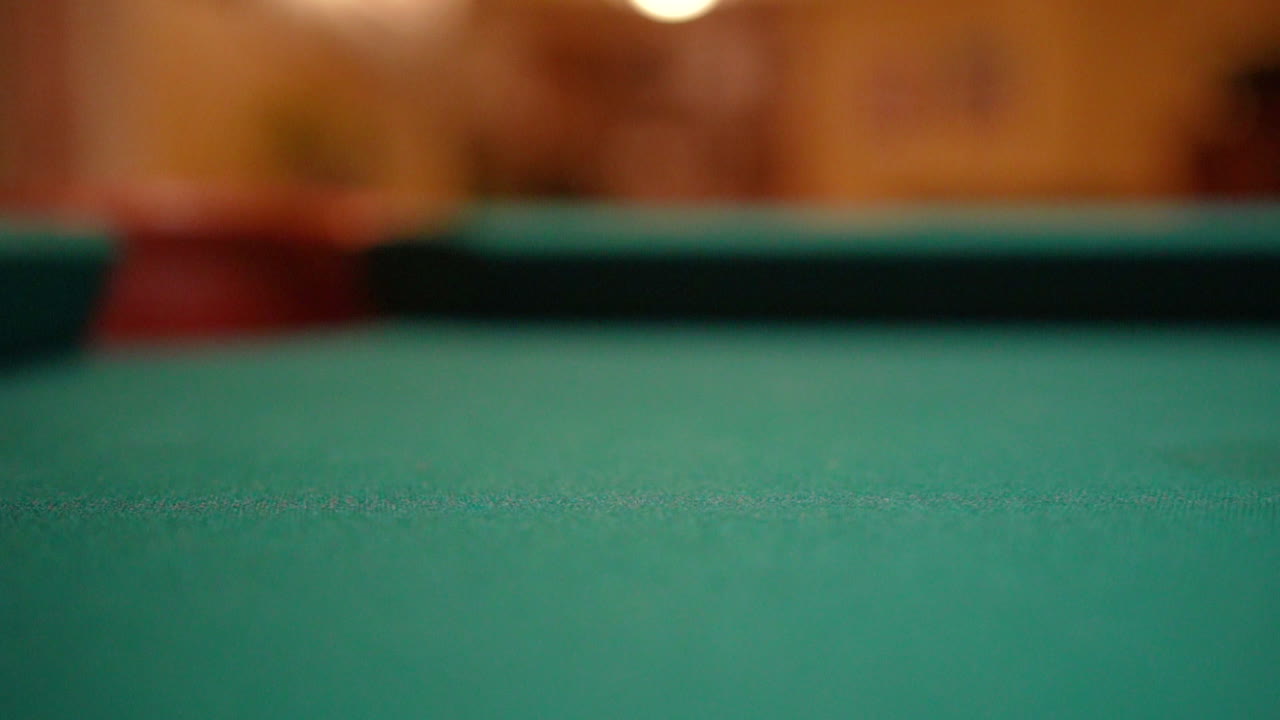 Slow Motion Billiards solid yellow 1 ball shot in corner pocket on pool table with green felt and brown pockets with the cue ball sliding out of frame Low Angle Close Up with Red Spinning Dots