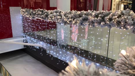 decorated shopping mall glass balustrade with snow covered christmas pines and twinkling lights with hologram butterfly effect in 4k
