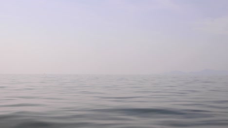 view from a ship travelling across a calm, foggy ocean.