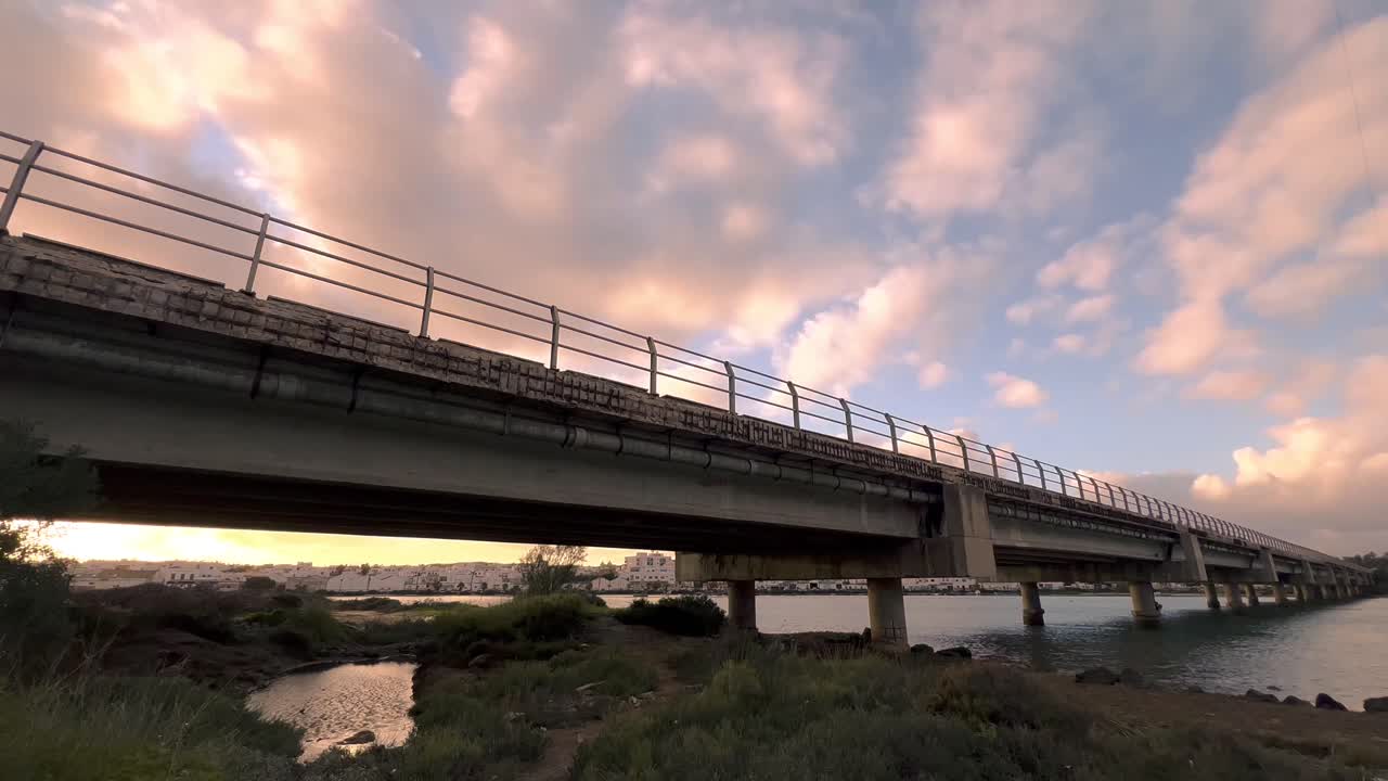 Captivating time-lapse sequence, the ever-changing dance of clouds unfolds against the sturdy backdrop of a concrete bridge, spanning gracefully across the scene
