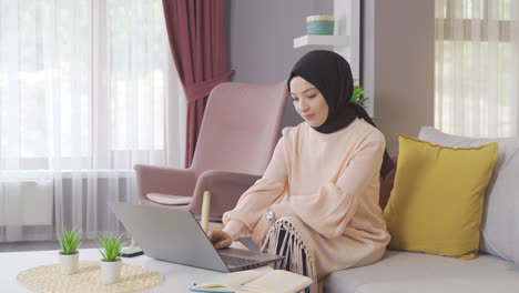 Una-Joven-Musulmana-árabe-Con-Hijab-Está-Usando-Una-Computadora-Portátil-En-Casa.