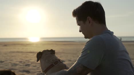 man sitting with his dog on the beach in slow motion.