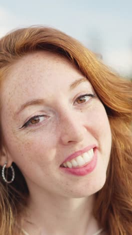 close-up portrait of a smiling young woman with red hair and freckles