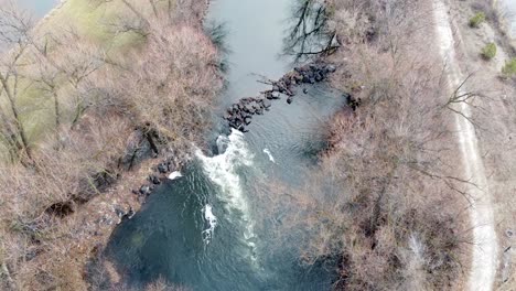 small river dam and rapids on scenic, idyllic, willow tree lined river in winter in rural countryside in boise, idaho, usa