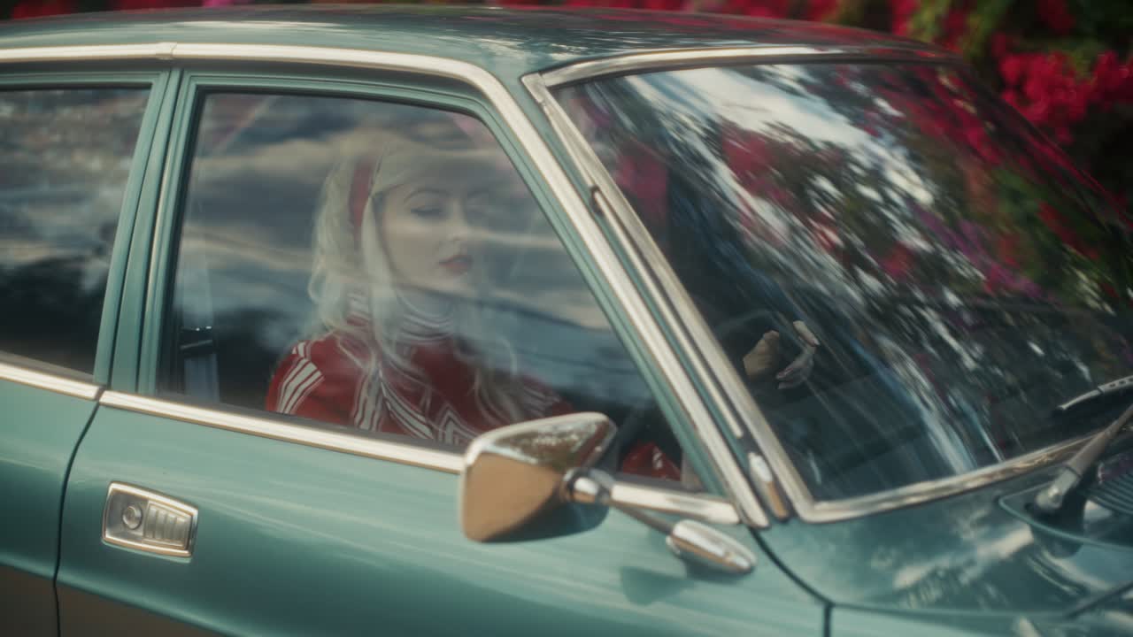 Stylische Frau sitzt in einem Oldtimer auf einer Straße
