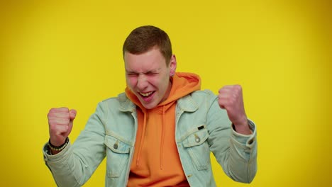 Teen-man-in-denim-jacket-shouting,-raising-fists-in-gesture-I-did-it,-celebrating-success,-winning