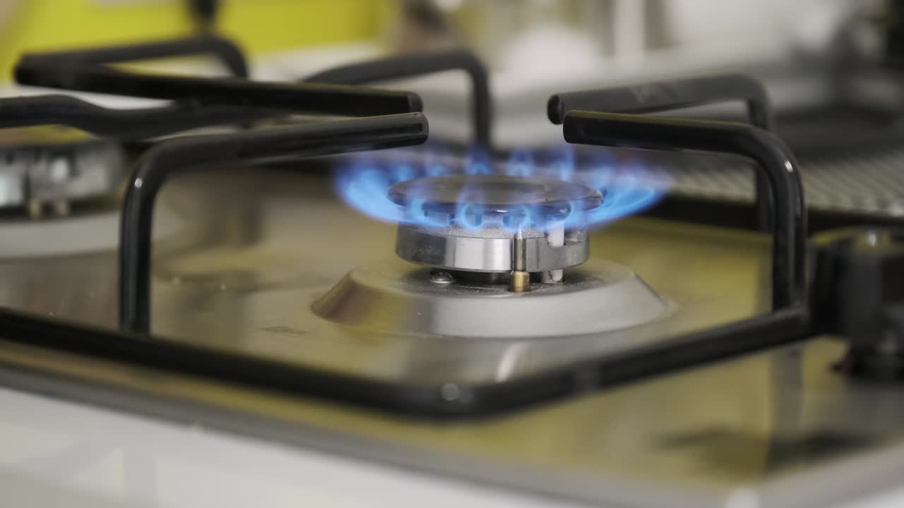 부에서 가스 버너에 불을 끄는 여성의 손, 불타는 버너의 클로즈업.