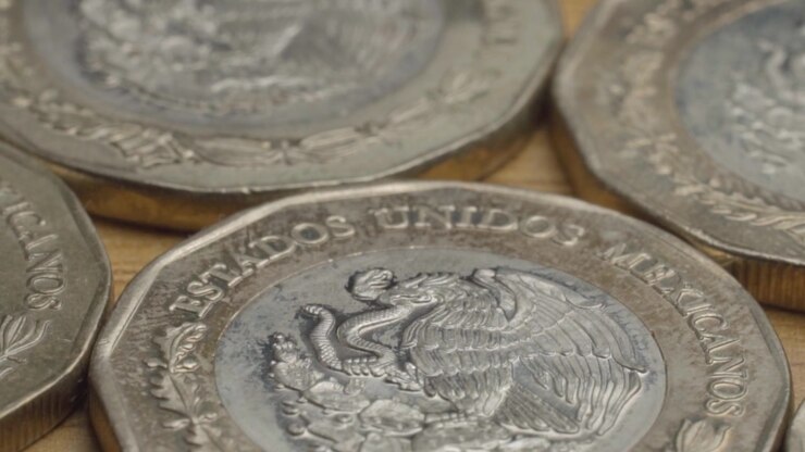 Primo piano macro di monete in pesos messicani disposte su una superficie, che mette in evidenza lo stemma dell'aquila in rilievo, l'iscrizione nazionale messicana, i dettagli incisi e la texture metallica